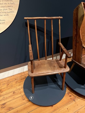 A blond-timber armchair with a gently curved crest.