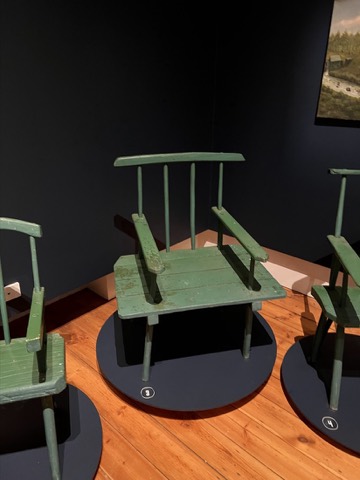A green-painted chair on a museum platform.