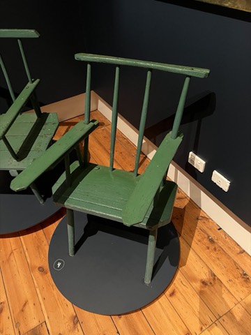 A green-painted chair with notched arms and extra legs.